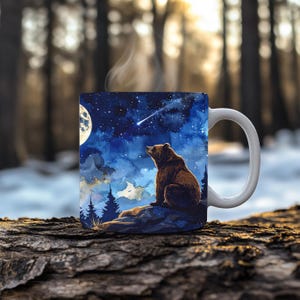 May include: White ceramic mug with a watercolour illustration of a brown bear looking up at a starry night sky and a shooting star. The mug has a curved handle and contains a steaming beverage, suggesting warmth and comfort.
