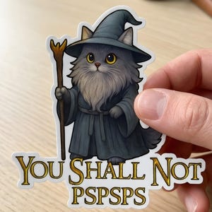 Puede incluir: Una pegatina con un gato de dibujos animados vestido de mago, con un sombrero y una túnica grises, sosteniendo un bastón. La pegatina tiene el texto "YOU SHALL NOT PSPSPSPS" en letras doradas.