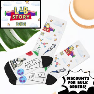 May include: White socks with black heels and toes, featuring science-themed graphics like a microscope, beakers, and molecular structures. The socks have the text "LAB STORY 2026" and "26" printed on them. The image also includes the text "DISCOUNTS FOR BULK ORDERS!"