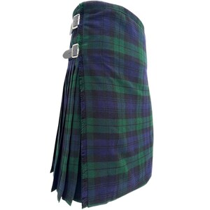 Könnte beinhalten: Ein traditioneller Kilt in einem grün- und marineblauen Karomuster. Der Kilt hat Falten, Fransen und Lederriemen mit silbernen Schnallen. Das Kleidungsstück ist für einen klassischen, formellen Look konzipiert.