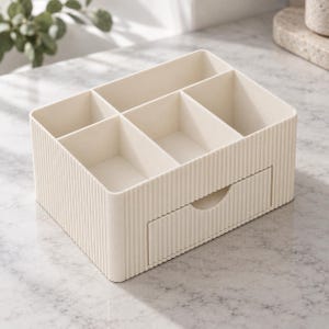 May include: A cream-colored plastic desk organizer featuring a ribbed exterior texture. The unit includes five open-top compartments of varying sizes on the upper level and a single pull-out drawer at the bottom with a semi-circular cutout handle.