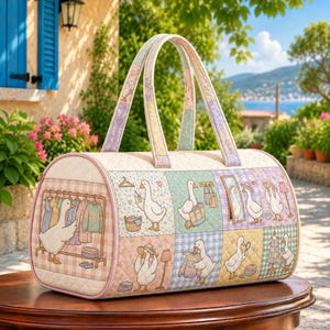 May include: A quilted barrel-shaped duffel bag featuring a patchwork design with illustrations of white geese in various activities. The bag has two top handles, a light pink trim, and a pattern of pastel-colored squares with gingham and floral prints.