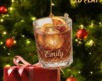 Può includere: Un ornamento natalizio piatto 2D trasparente a forma di bicchiere da cocktail. Il bicchiere è riempito con una bevanda, ghiaccio e guarnizioni. Il nome "Emily" è scritto sul bicchiere in oro. L'ornamento è appeso a un filo d'oro, con la scritta "2D FLAT" in alto a destra.