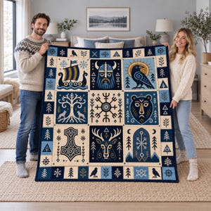 Peut inclure: Un plaid rectangulaire présentant une grille d'illustrations d'inspiration nordique, notamment un drakkar, un personnage casqué, un corbeau, un arbre, un ours, un cerf et un marteau, le tout dans des tons bleu, crème et doré.