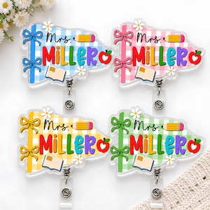 May include: Four acrylic badge reels featuring a gingham pattern in blue, pink, yellow, and green. Each displays the text Mrs. MILLER, a yellow pencil, an open book, a red apple, and two small white daisies with two matching bows on the side.