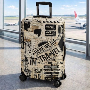 Pode incluir: Uma mala de rodinhas com fundo creme apresentando gráficos de viagem em estilo vintage preto, mapas e textos incluindo "HERE WE GO!", "TRAVEL", "EXPLORE", "SPEED LIMIT 55" e "CAMPGROUND". Possui uma alça retrátil preta e rodinhas.
