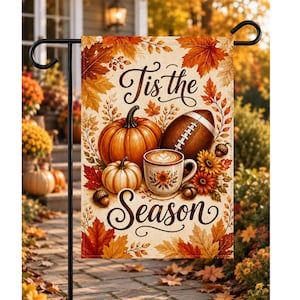 Pode incluir: Uma bandeira de jardim retangular com o texto 'Tis the Season' em letra elegante. O design apresenta uma abóbora laranja grande, uma abóbora branca menor, uma bola de futebol americano, uma caneca de café e folhas de outono com bolotas.