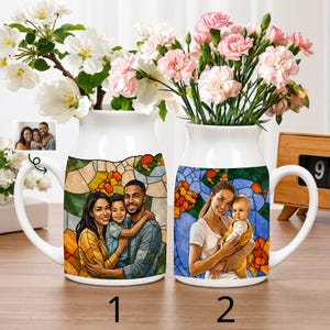 Könnte beinhalten: Zwei weiße Keramikbecher mit Familienporträts im Buntglasstil. Ein Becher zeigt eine dreiköpfige Familie, der andere eine Mutter und ein Kind. Beide Becher haben große Henkel und sind mit Blumen gefüllt.