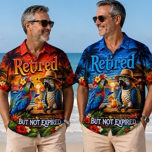 May include: Two short-sleeved button-down shirts featuring a tropical beach scene with parrots wearing hats, hibiscus flowers, and the text "Retired BUT NOT EXPIRED". One shirt has a warm orange and red sunset background, the other a cool blue.