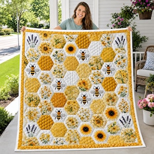May include: A quilt featuring a hexagonal patchwork design with alternating patterns of yellow sunflowers, purple lavender sprigs, and honeycombs. The quilt includes illustrations of black and yellow bees scattered throughout the hexagonal grid.