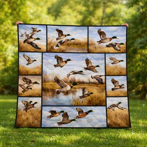 May include: A quilt featuring multiple panels with images of ducks in flight over a marshy landscape. The ducks are depicted with brown, white, and green plumage, set against a backdrop of water, reeds, and a cloudy sky. The quilt is bordered in black.