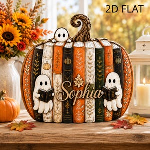 Puede incluir: Un objeto decorativo con forma de calabaza compuesto por lomos de libros verticales en naranja, blanco, negro y verde. Presenta tres figuras de fantasmas blancos, dos sosteniendo libros pequeños, y el nombre Sophia en cursiva. Tallo rizado.