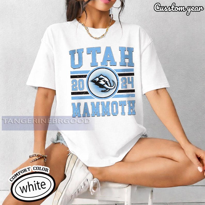 May include: White t-shirt with a light blue graphic that says "UTAH MAMMOTH 2024". The graphic includes a circular emblem with an elephant design. The shirt has a crew neck and short sleeves.