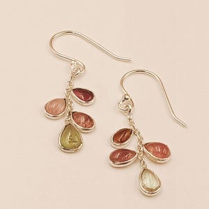 Pode incluir: Um par de brincos pendurados em prata. Cada brinco apresenta um grupo de quatro gotas de pedras preciosas em tons de rosa, vermelho e verde. As pedras são em forma de gota e ovais.