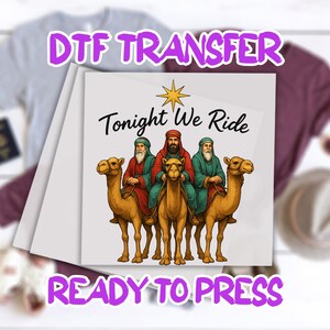 May include: A DTF transfer featuring three figures riding camels, with the text "Tonight We Ride" and a star graphic. The words "DTF TRANSFER" and "READY TO PRESS" are also visible.