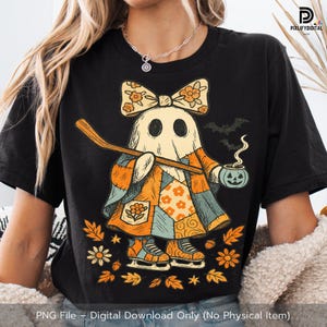 May include: Black t-shirt featuring a cartoon ghost in a patchwork outfit, holding a hockey stick and a jack-o'-lantern. The ghost wears a floral bow and ice skates. Autumn leaves and bats surround the ghost. Text at the bottom reads "PNG File - Digital Download Only (No Physical Item)".