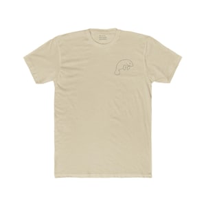 May include: A light beige t-shirt with a small, minimalist manatee outline on the upper left chest. The shirt has a crew neck and short sleeves. The manatee design is a simple, thin black line.