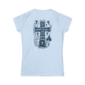 May include: Pale blue t-shirt with a navy blue cross design on the back. The cross features the text "All it takes faith, trust, and a little bit of pixie dust" with fairy and castle illustrations.