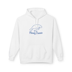 May include: White hoodie with a front pocket and drawstring. The hoodie features a blue line drawing of a manatee above the text "The Floaty Potato" in blue. The hoodie is made of a soft material.