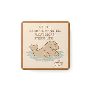 May include: Square coaster with a light brown border and a cream-coloured centre. The centre features a cartoon manatee floating in water, with the text "LIFE TIP: BE MORE MANATEE. FLOAT MORE. STRESS LESS." and the logo "The Floaty Potato."