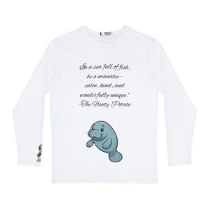 May include: White long-sleeved shirt with a cartoon manatee and the quote, "In a sea full of fish, be a manatee - calm, kind, and wonderfully unique." The shirt also has the text "-The Hoaty Potato."