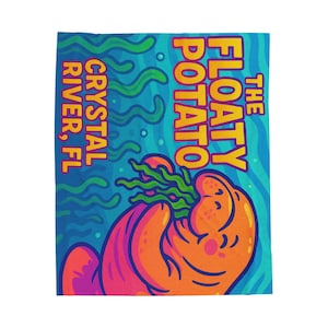 May include: A colourful blanket with a cartoon illustration of a smiling orange potato holding green seaweed. The text "THE FLOATY POTATO" and "CRYSTAL RIVER, FL" are displayed in bold fonts against a blue background.
