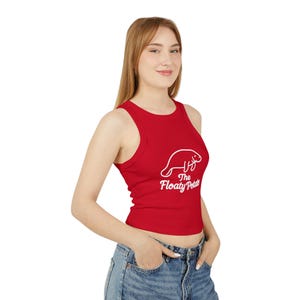 May include: A red ribbed tank top featuring a white manatee graphic and the text "The Floaty Potato". The sleeveless, cropped top is made of a soft material.