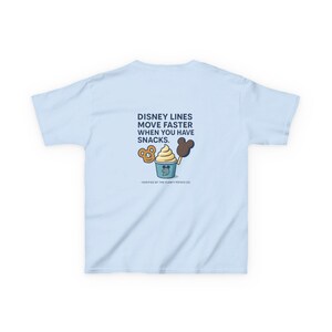 May include: Pale blue t-shirt featuring the text "DISNEY LINES MOVE FASTER WHEN YOU HAVE SNACKS." The design includes a cartoon pretzel, ice cream bar, and ice cream cup. The text "-VERIFIED BY THE FLOATY POTATO CO." is at the bottom.