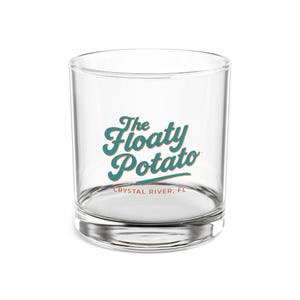 May include: A clear glass tumbler with a rounded base. The words "The Floaty Potato" are printed in teal script with a teal and gold accent. Below the text is "CRYSTAL RIVER, FL" in a smaller font.