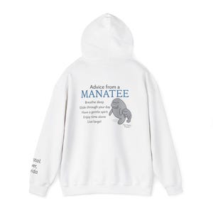 May include: White hooded sweatshirt with the text "Advice from a Manatee" and a cartoon manatee graphic. The sweatshirt also features the phrases "Breathe deep, Glide through your day, Have a gentle spirit, Enjoy time alone, Live large!"