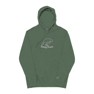 May include: A green hooded sweatshirt with a kangaroo pocket and a drawstring hood. The front displays a white graphic of a manatee and the text "The Floaty Potato". The sweatshirt is made of a soft material.