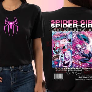 May include: Black t-shirt with a pink spider logo on the front. The back has a comic-style Spider-Girl graphic with "SPIDER-GIRL" text and "MARVEL". The shirt includes Spanish text and a barcode.