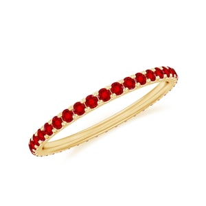 Peut inclure: Une bague en or ornée d'une rangée continue de pierres précieuses rouges vives. La bague présente un anneau en or poli et les pierres sont espacées uniformément.