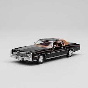 May include: A black and tan classic car model with chrome accents. The miniature vehicle features a brown roof, a detailed interior, and a shiny black exterior. The car has a rectangular chrome grill and silver rims.