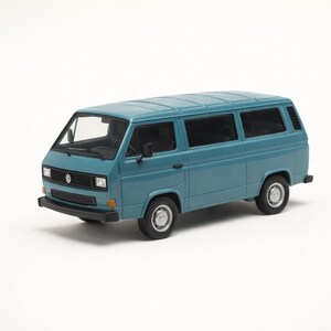 May include: A teal-colored model of a classic Volkswagen van. The miniature vehicle features detailed windows, tires, and a front grill with the Volkswagen logo. The van is a light blue-green color and sits on a white surface.