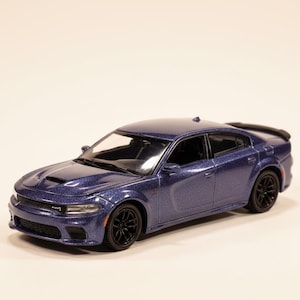 May include: A blue model car with a glittery finish. The car has black wheels and a spoiler. The front of the car has a hood scoop and detailed headlights. The car is a miniature replica of a sedan.