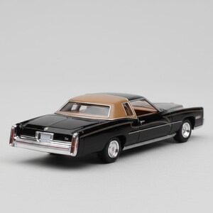 May include: A black and tan classic car model with chrome accents. The miniature vehicle features a tan roof, black body, and detailed interior. The model car is a vintage collectible.