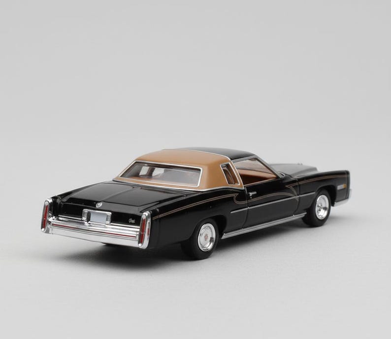 May include: A black and tan classic car model with chrome accents. The miniature vehicle features a tan roof, black body, and detailed interior. The model car is a vintage collectible.