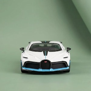 May include: A white and black toy sports car with blue accents. The car has a black front grill and a black stripe down the center. The car has a sleek, aerodynamic design.
