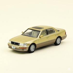 May include: A gold and brown model car with a sunroof. The car has a license plate that reads "4 80". The car has a two-tone paint job, with a gold upper body and a brown lower body. The car has black tires and silver rims.