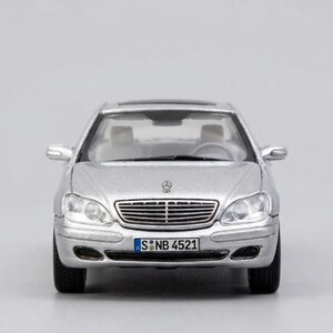 May include: Silver model car with a black roof and license plate reading "S NB 4521". The car has a chrome grill and headlights. The car is a miniature replica of a sedan.