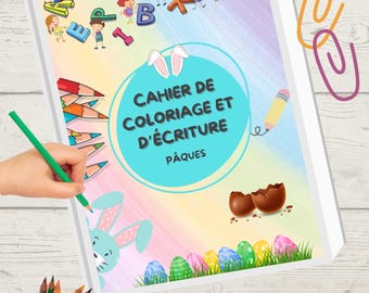 Pode incluir: Um livro para colorir e escrever com o texto "CAHIER DE COLORIAGE ET D'ÉCRITURE PÂQUES" é mostrado com uma mão segurando um lápis verde. A capa apresenta ilustrações temáticas da Páscoa, incluindo um coelho, ovos e crianças. Lápis de cor também são visíveis.