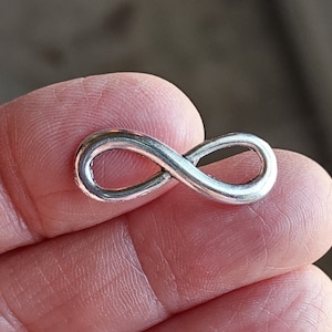 May include: A silver infinity symbol charm. The charm is a simple, continuous loop design.