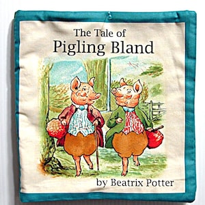 May include: A square, off-white fabric item with a teal border features the title "The Tale of Pigling Bland" and illustrations of two anthropomorphic pigs. The artwork is in a storybook style, with text by Beatrix Potter.
