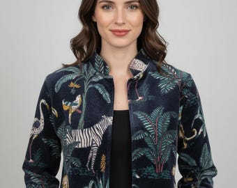 Könnte beinhalten: Eine dunkelmarineblaue Samtjacke mit einem lebendigen Dschungel-Print, der weiße Zebras, Flamingos sowie verschiedene tropische Palmenblätter und Pflanzen zeigt. Die Jacke hat einen hohen Kragen, lange Ärmel und ein offenes Vorderteil.