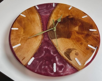 May include: A round wooden clock with a burgundy resin center. The clock face features light brown wood segments and white hour markers. Gold-colored hands indicate the time. The clock is a decorative home decor item.