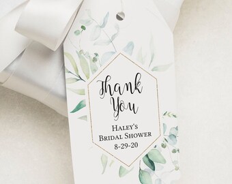 May include: A white gift box with a white satin ribbon and a green leafy sprig. A white gift tag with a gold hexagon frame and green watercolor leaves reads "Thank You Haley's Bridal Shower 8-29-20".