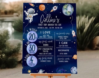 May include: A blue and white baby milestone poster with a space theme. The poster features an astronaut, planets, stars, and rockets. It includes information about the baby's weight, height, age, favorite things, and first words. The poster is titled "Collin's First Trip Around the Sun".