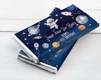 May include: Blue and white chocolate bar wrapper with an astronaut, planets, and stars. The text reads "Jump Among the Stars Liam's 4th Birthday".