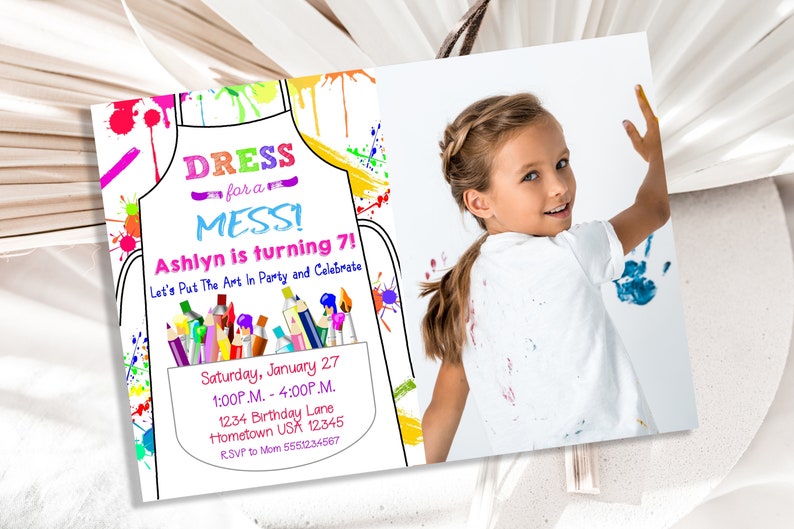 May include: A colorful invitation for a child's birthday party. The invitation features a cartoon drawing of an apron with paint splatters and art supplies. The text reads "Dress for a Mess! Ashlyn is turning 7! Let's Put The Art In Party and Celebrate. Saturday, January 27, 1:00P.M. - 4:00P.M. 1234 Birthday Lane, Hometown USA 12345, RSVP to Mom 6551234567". A photo of a young girl with paint on her shirt is in the background.
